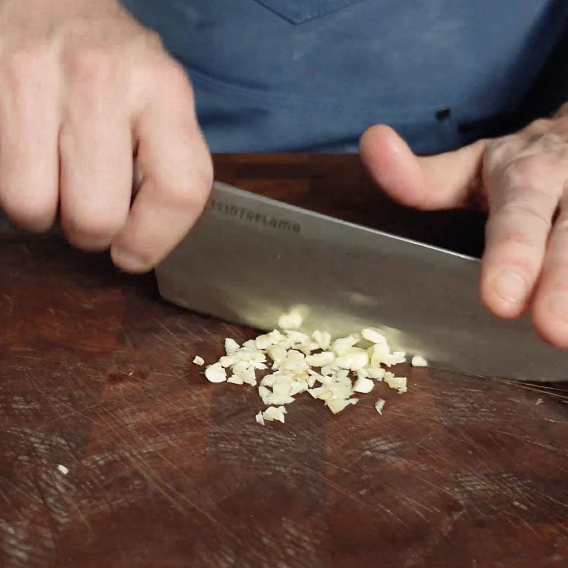 Chopping garlic with large blade.