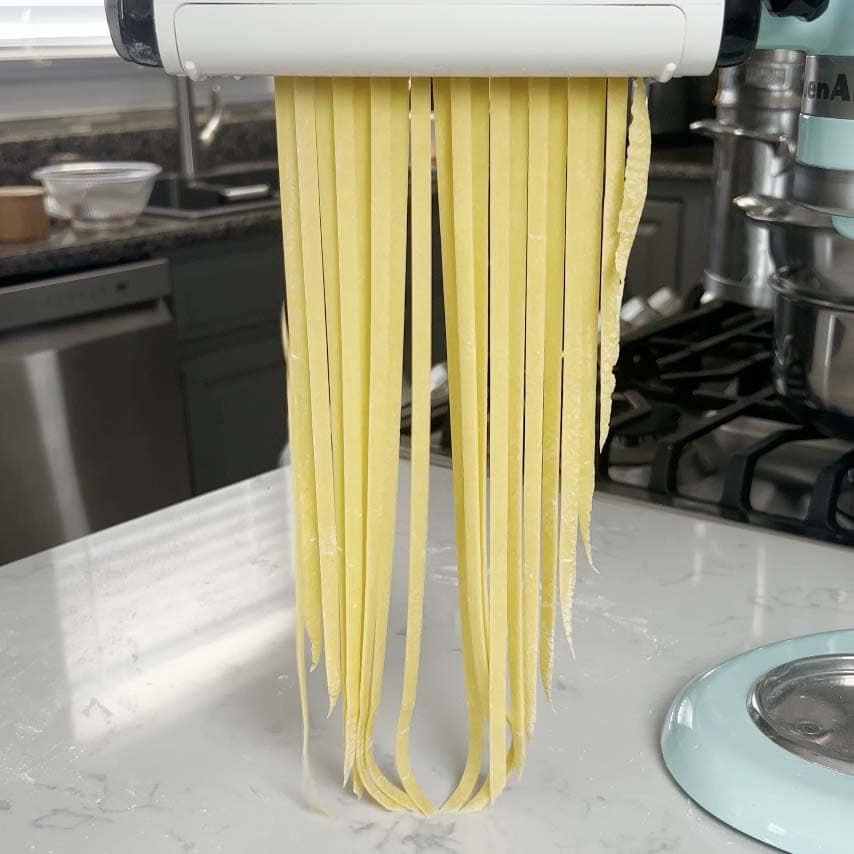 Homemade pasta going through a pasta maker.