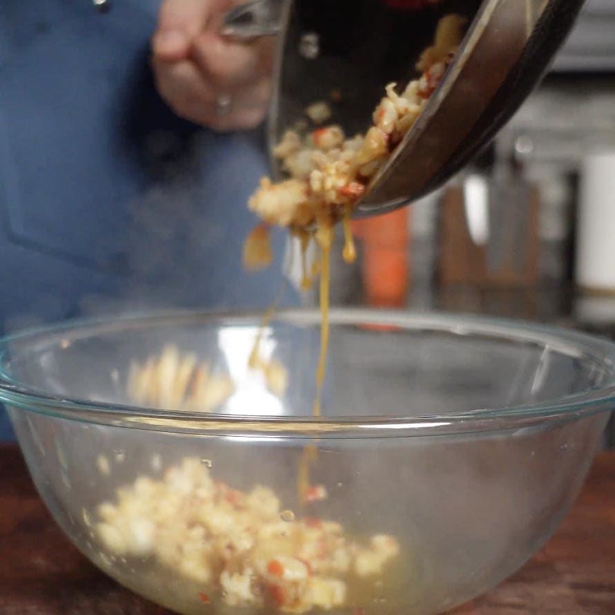 Placing cooked lobster into a mixing bowl.