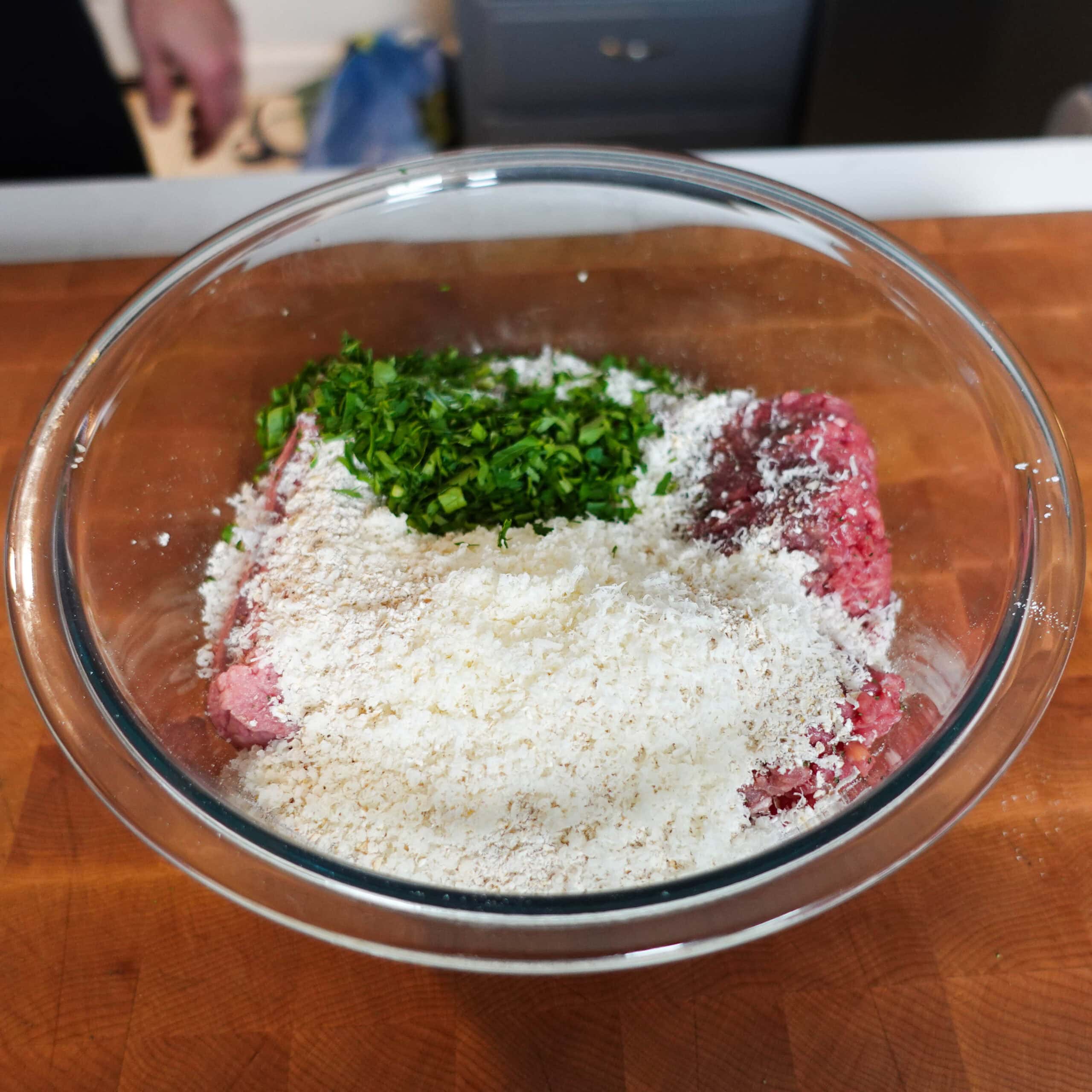Bread crumbs, meat and seasonings in a mixing bowl.