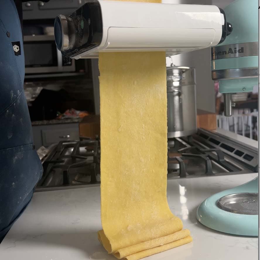 Pasta rolling through a pasta machine.