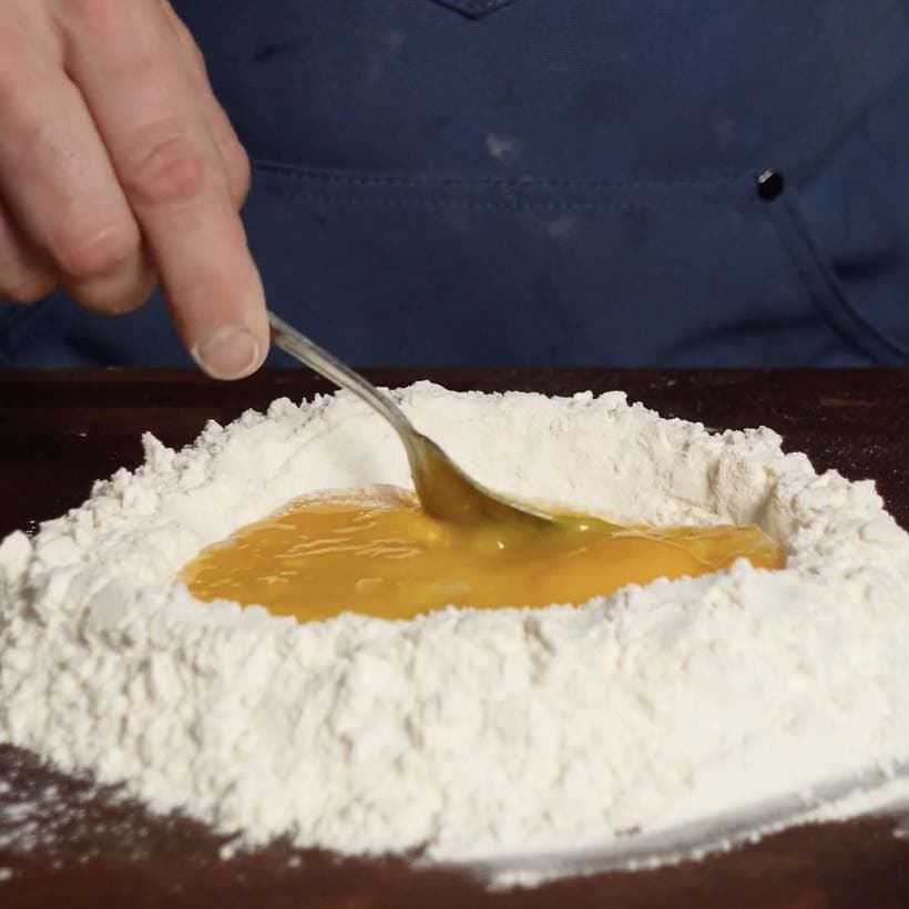 Stirring in egg yolks with a fork.