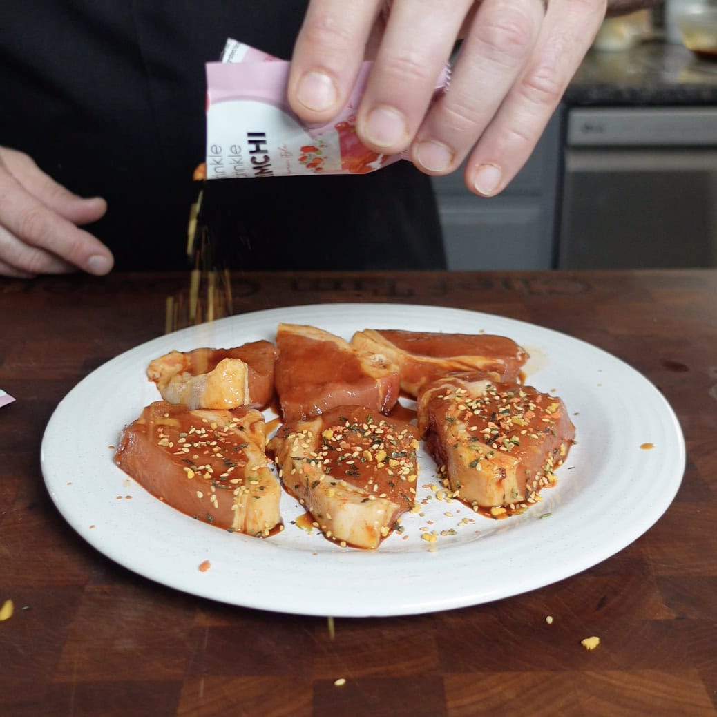 Kimchi seasoning going onto sliced pork.