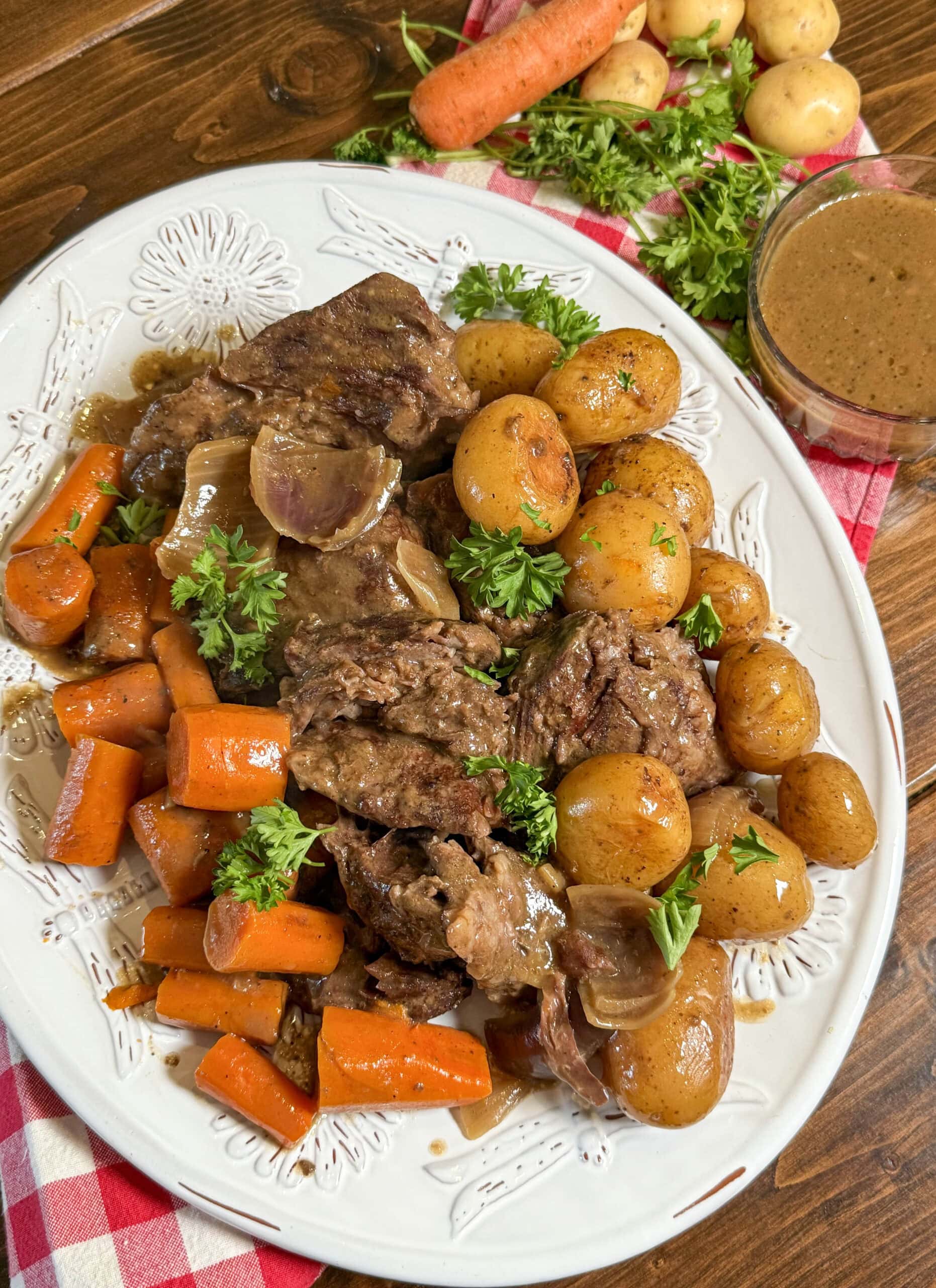 A plate full of roast, carrots, potatoes and cooked onions.