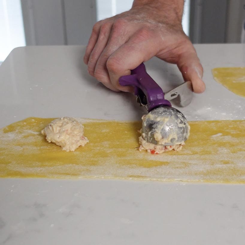 Lobster going onto a sheet of pasta.