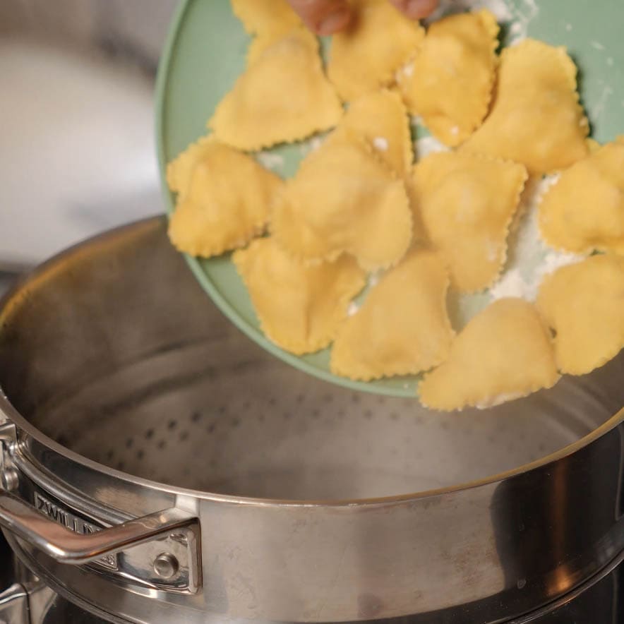 Ravioli going into a pot.