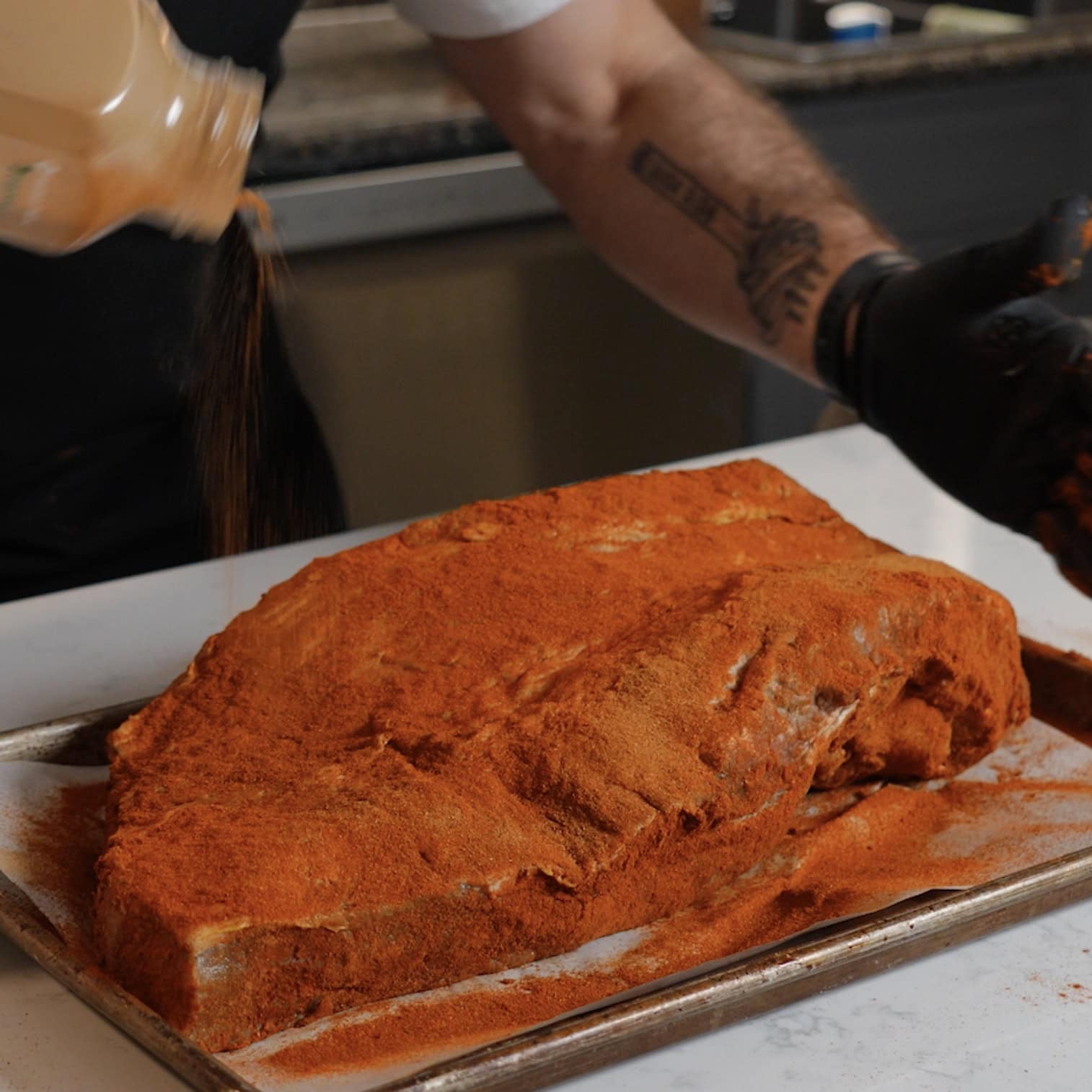 Seasoning the brisket on a cooking sheet.