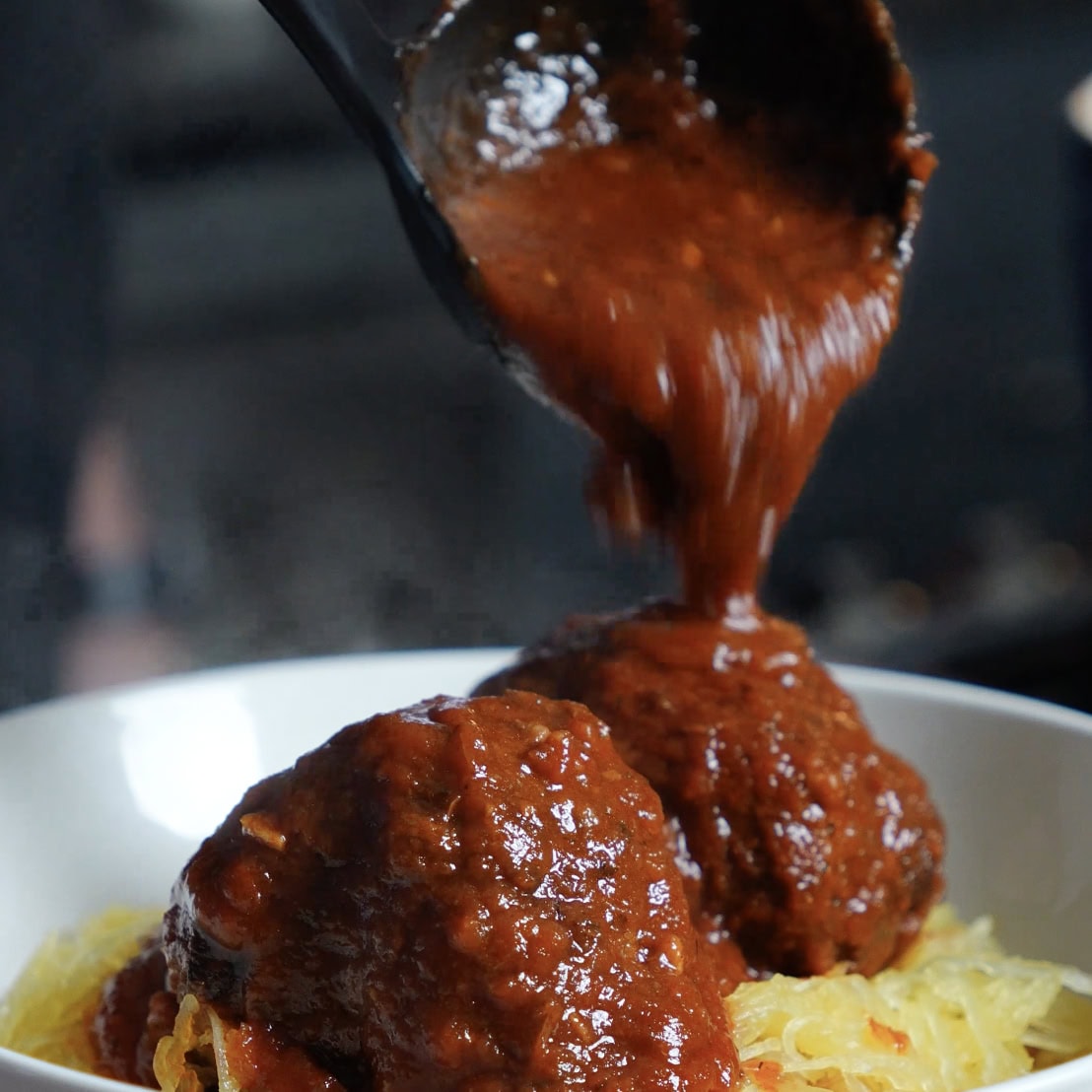 Spaghetti Sauxe pouring onto meatballs.