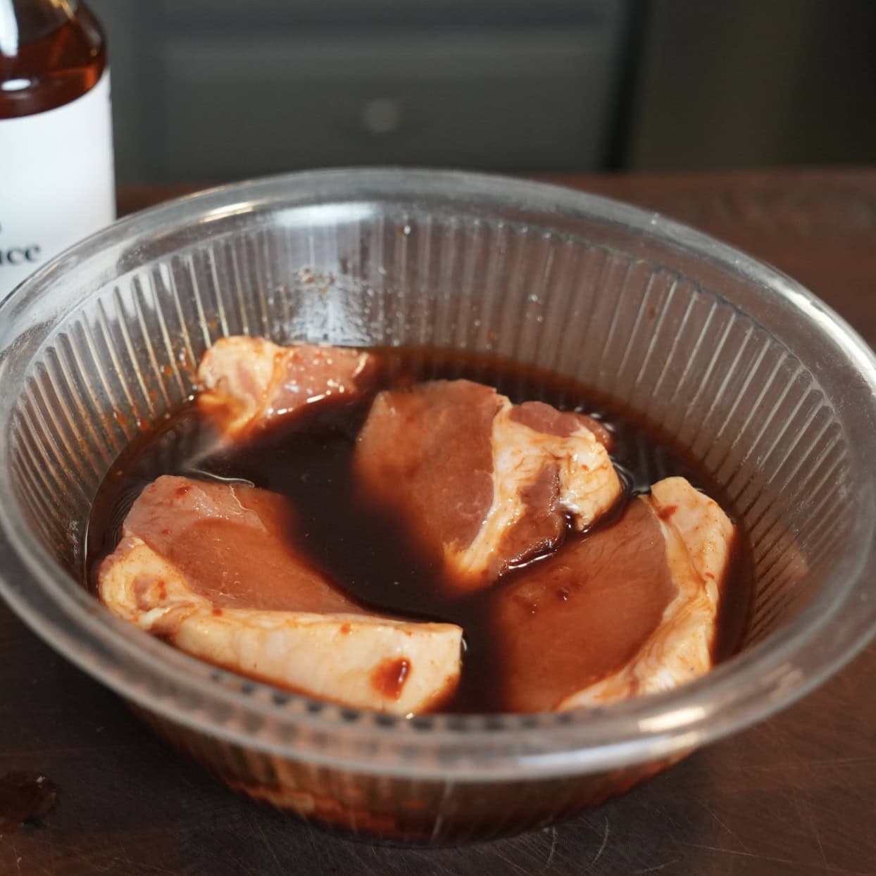 Pork marinating in a glass bowl.