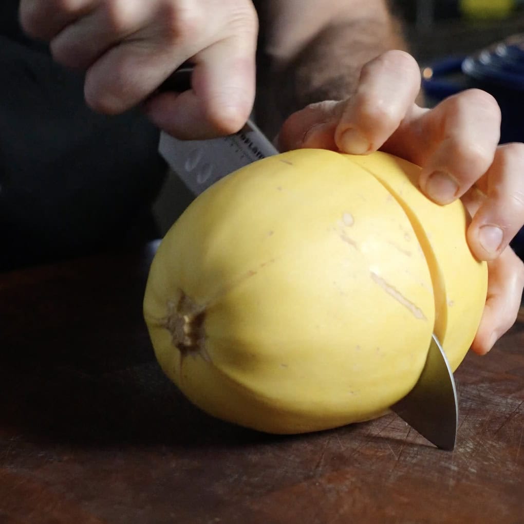 A spoon removing the seeds out of a Spaghetti Squash.
