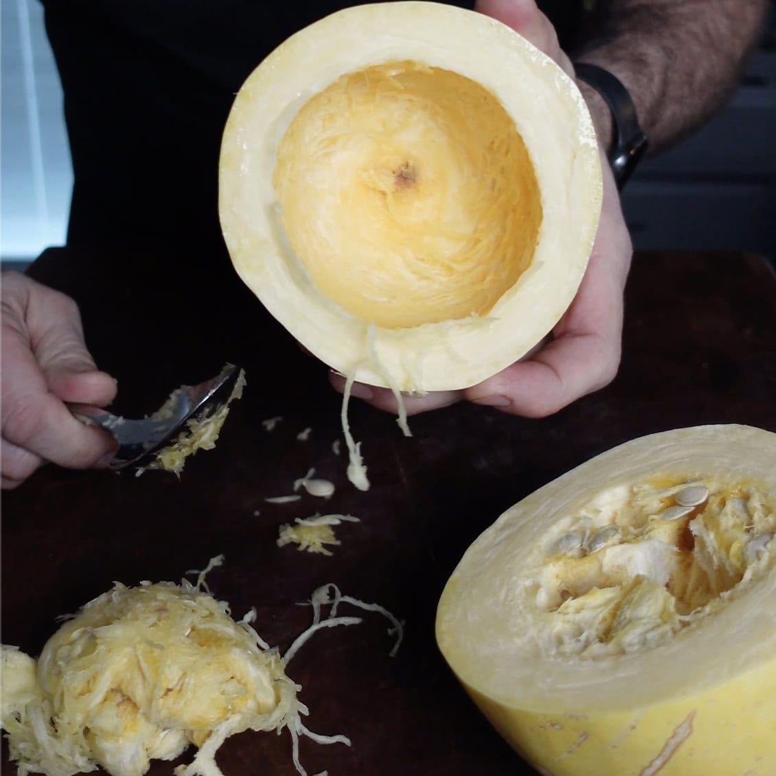 A spoon removing the seeds out of a Spaghetti Squash.