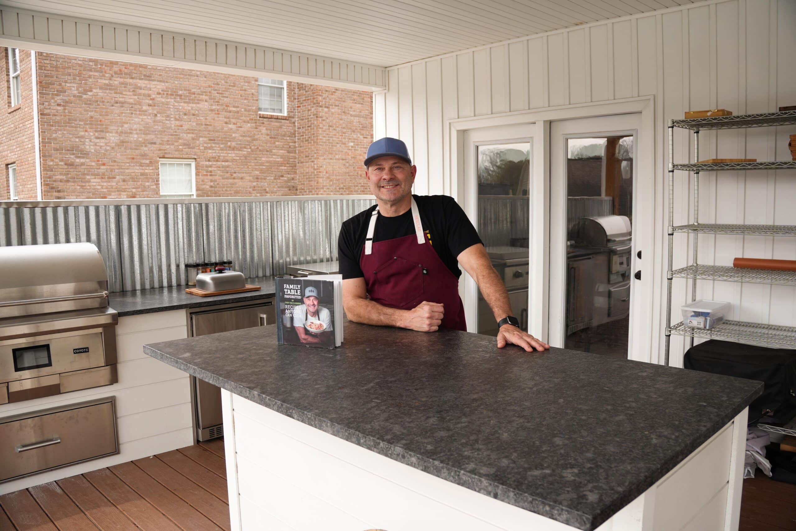 Tim in his outdoor kitchen with his cookbook.