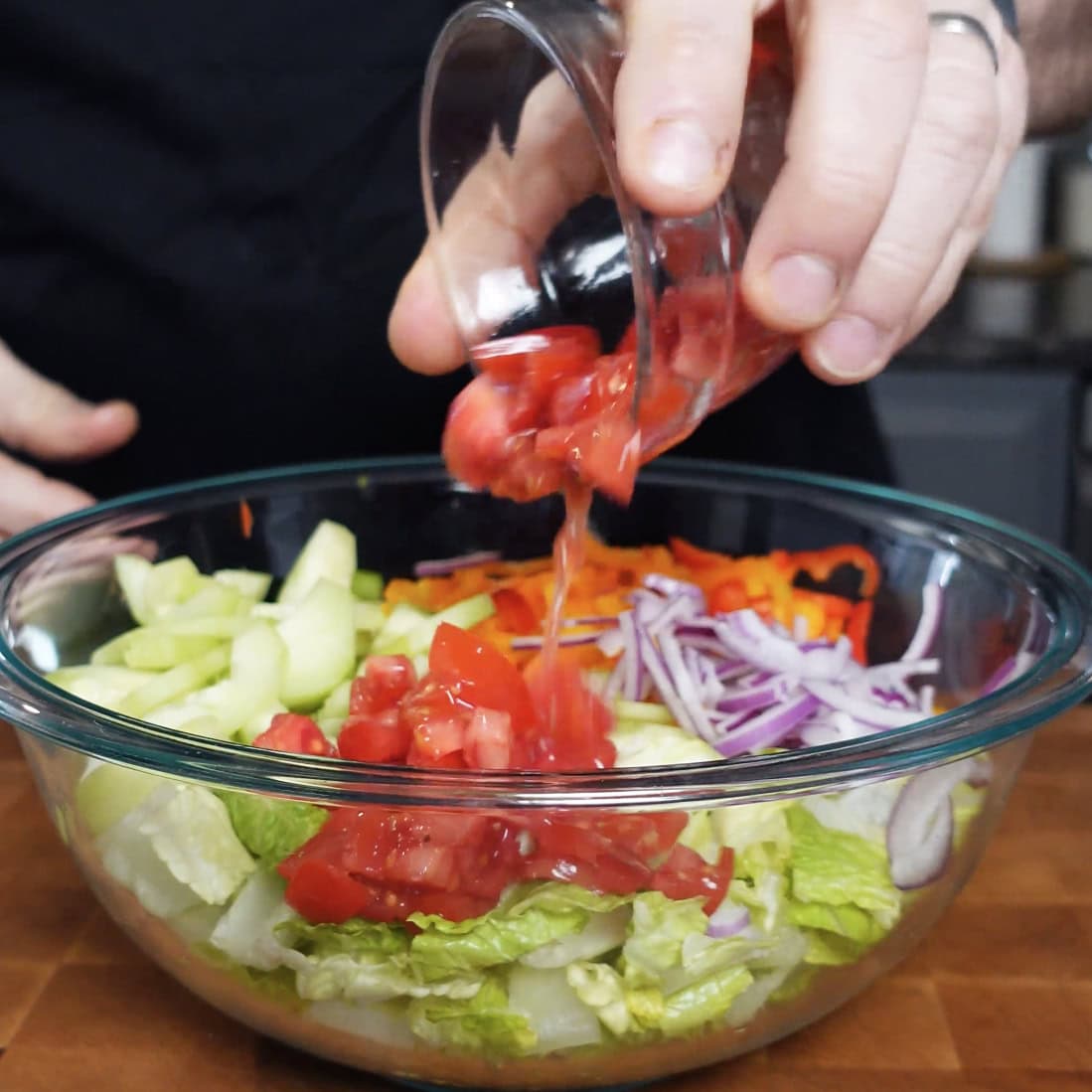 Tomatoes being placed onto a salad.