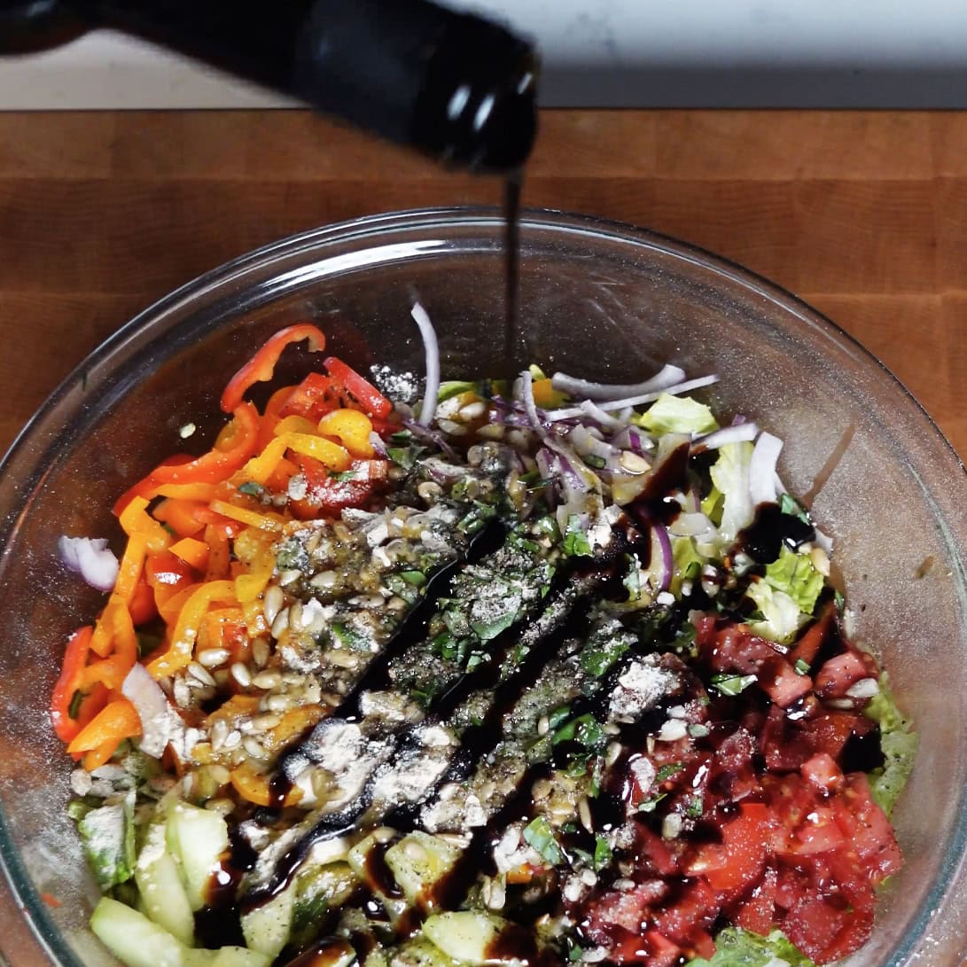 Balsamic dressing being drizzled onto salad.