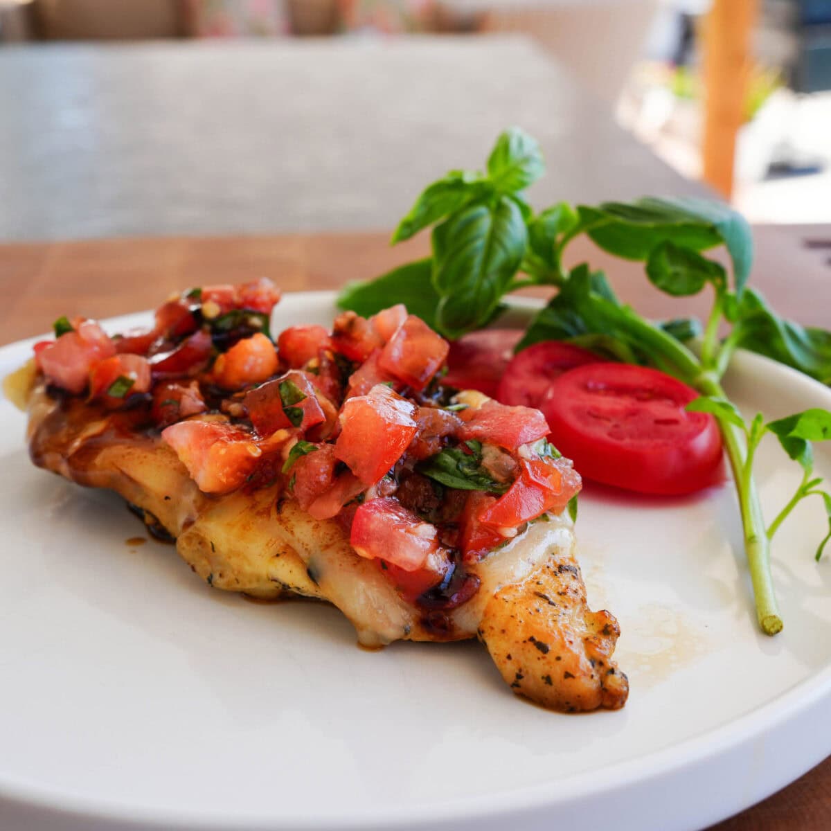 Bruschetta chicken on a white plate with drizzled balsamic vinegar.