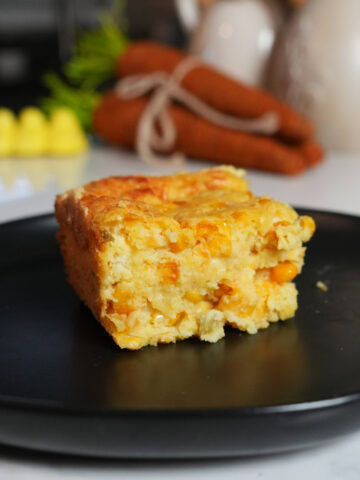 Corn casserole on a black plate.