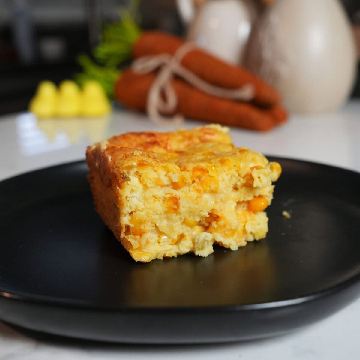 Corn casserole on a black plate.