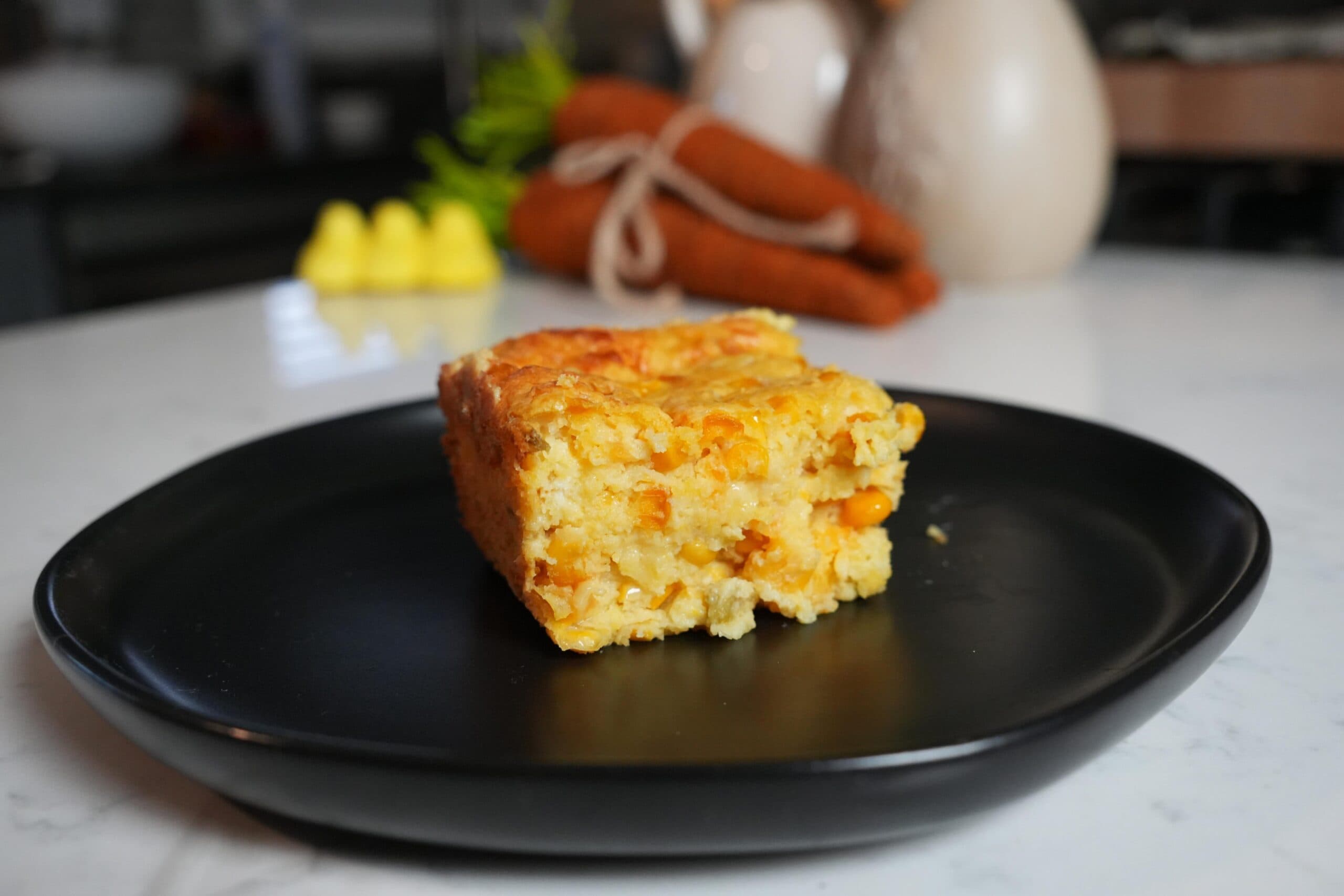 Slice of corn casserole on a black plate.