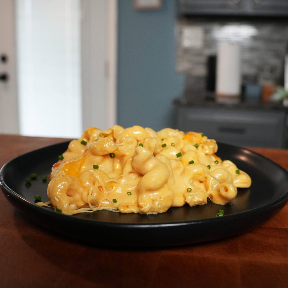 Creamy mac and cheese on a black plate.