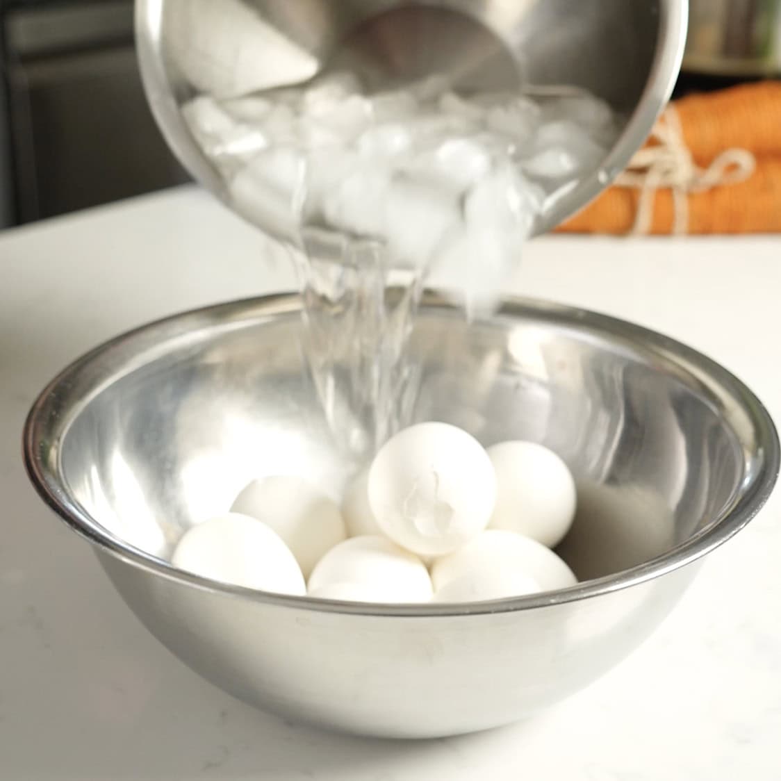 Cold water being poured over hard boiled eggs.