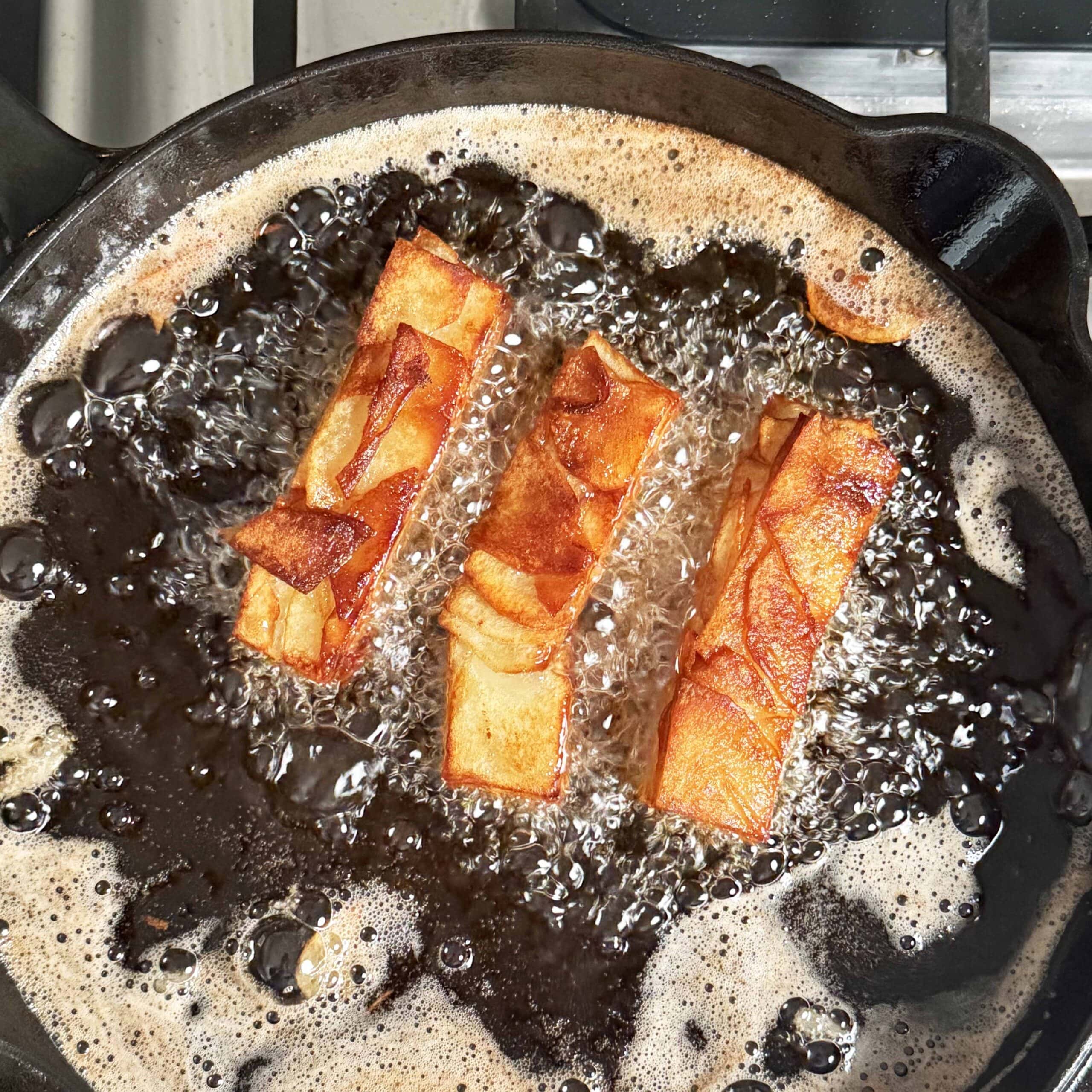 Frying potatoes in a skillet with oil.
