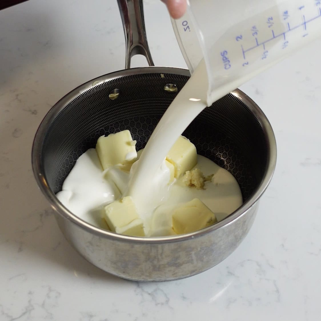 A stock pot with butter, garlic and milk.