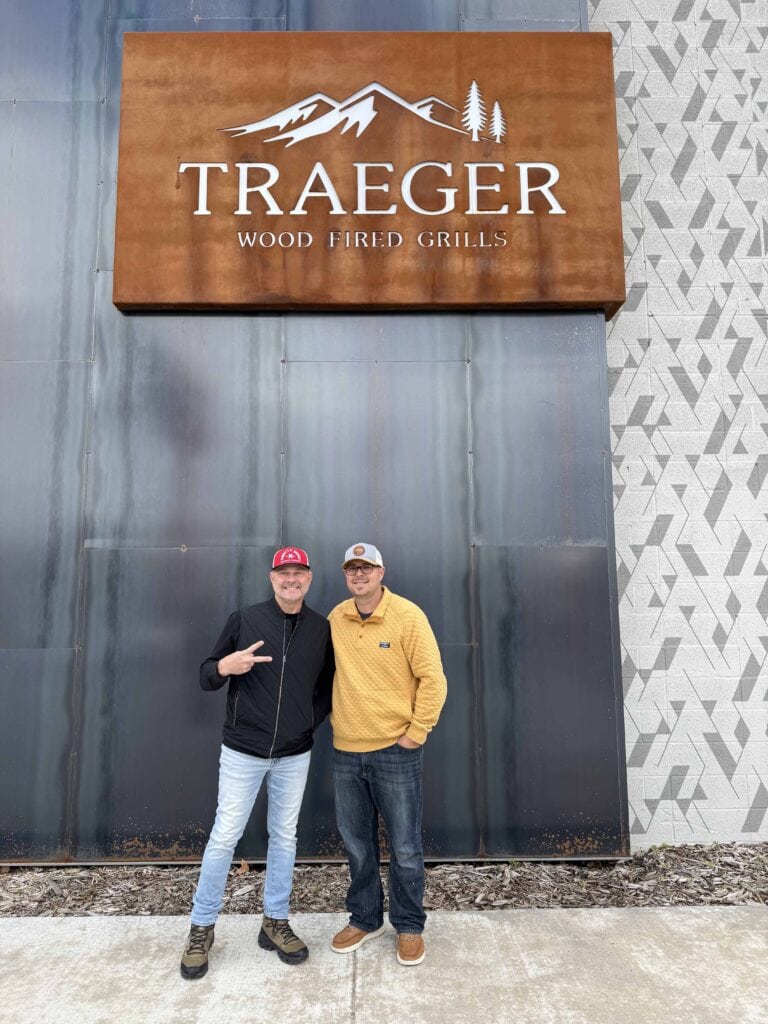 Tim and Neal in front of a Traeger sign.