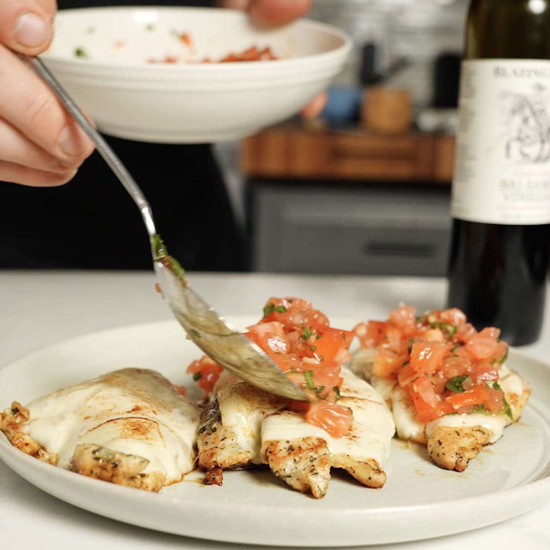 Placing bruschetta onto chicken breasts.