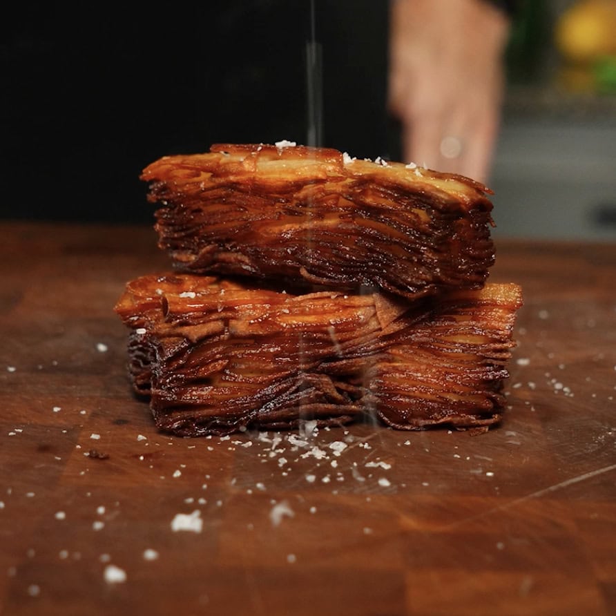 Fried potato stack on a cutting board with salt.