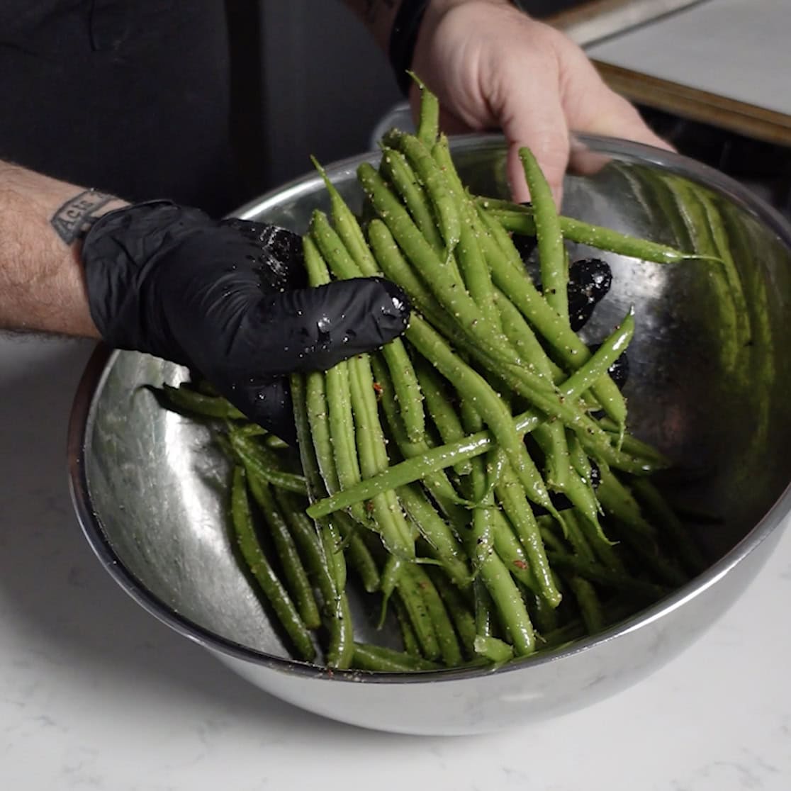 Seasoning green beans in a bowl.