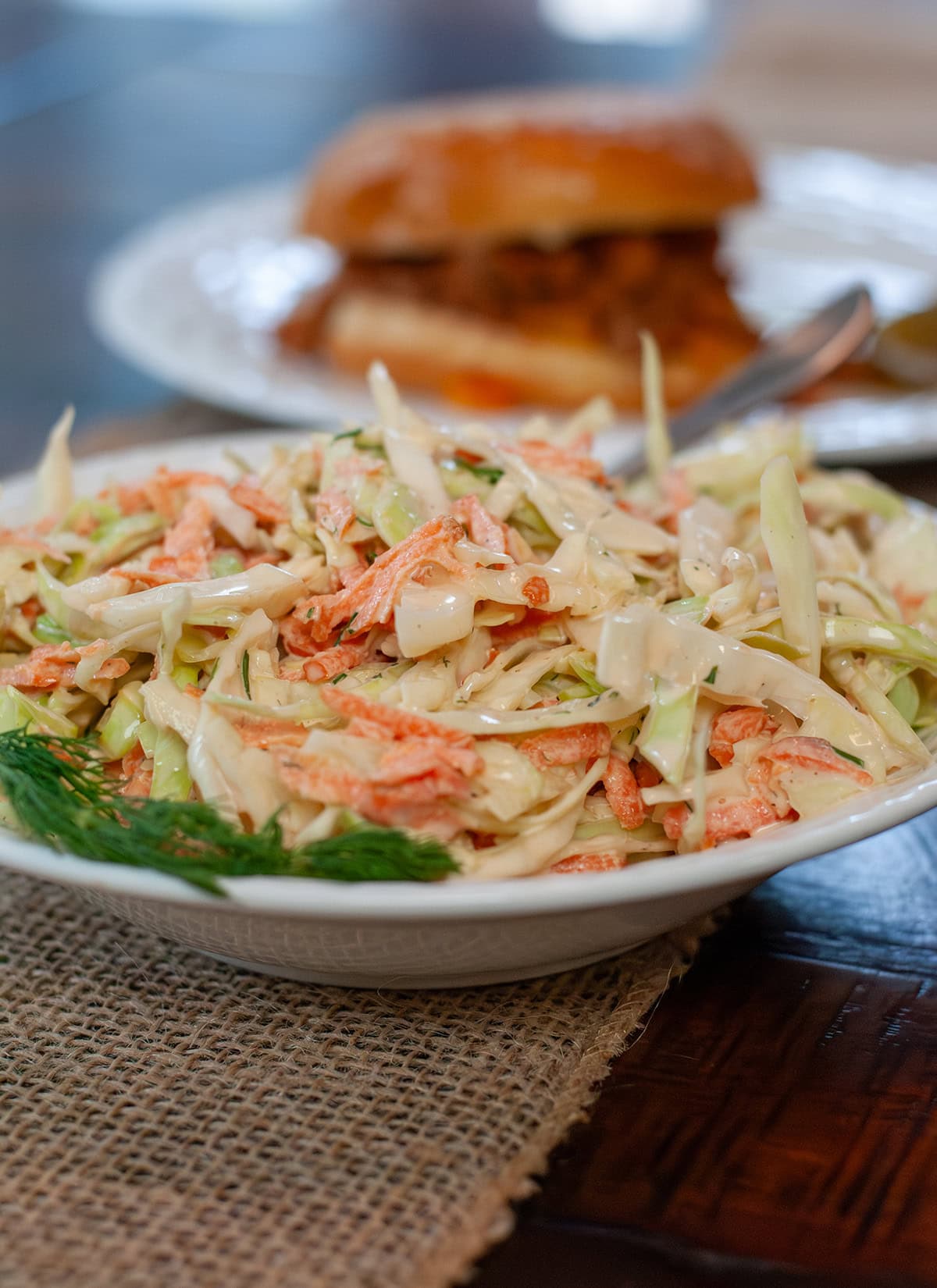 Coleslaw with a some fresh dill next to a sloppy Joe.