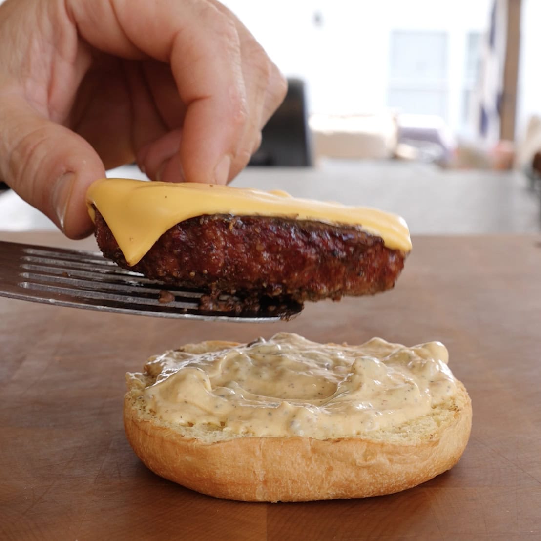 Placing a burger patty with cheese onto a bun.