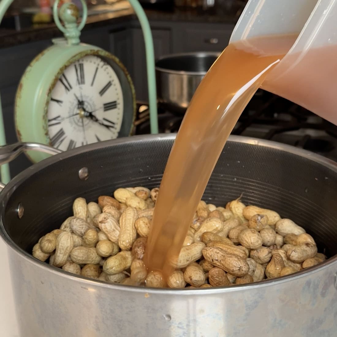 Pouring liquid into the crockpot full of peanuts.