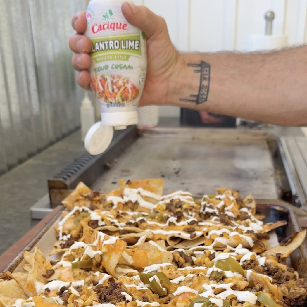 Cilantro Lime sauce being drizzled onto nachos.