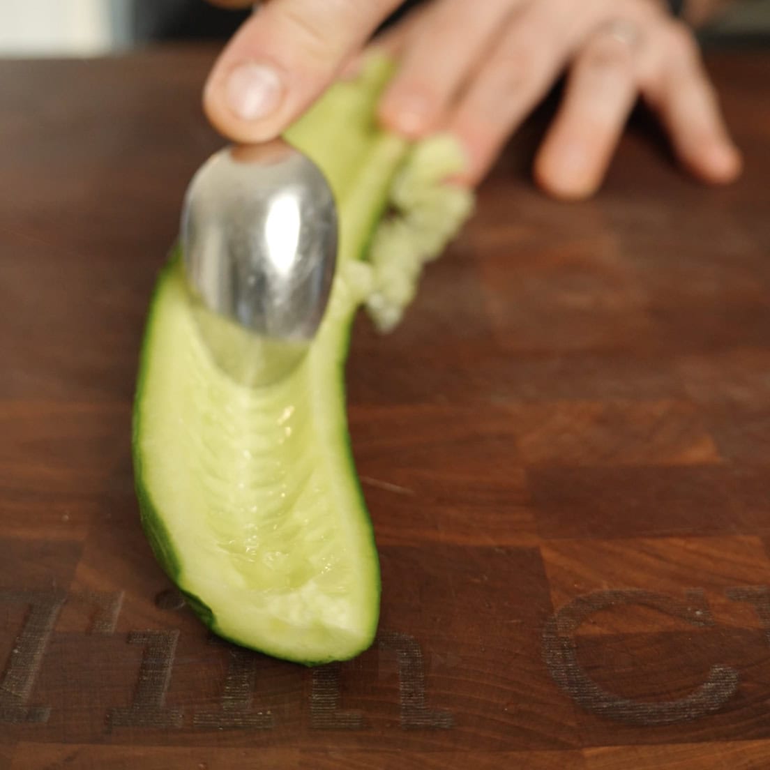 Removing the seeds from a cucumber with a spoon.