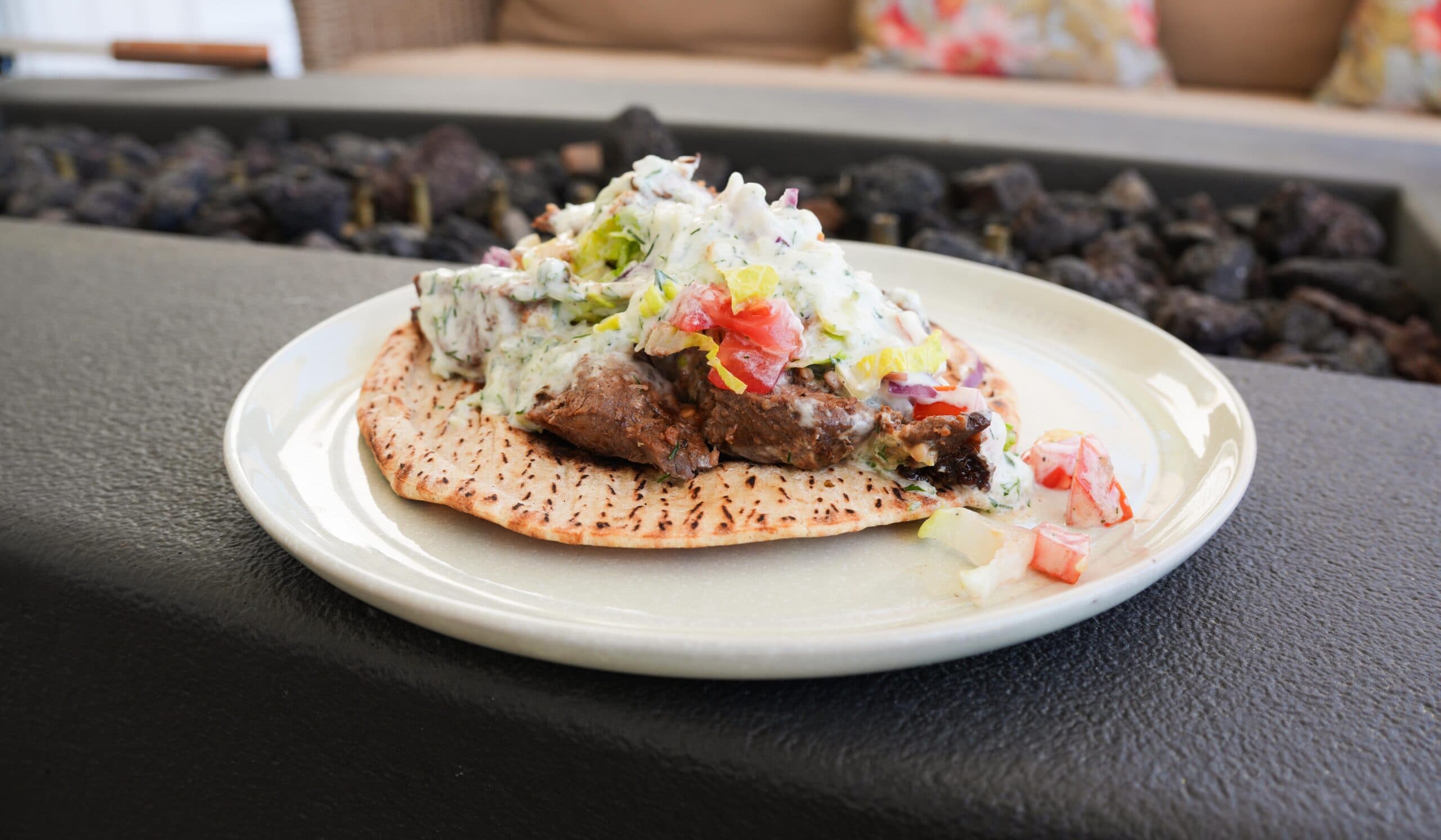 Tzatziki Sauce on a gyro on a white plate.
