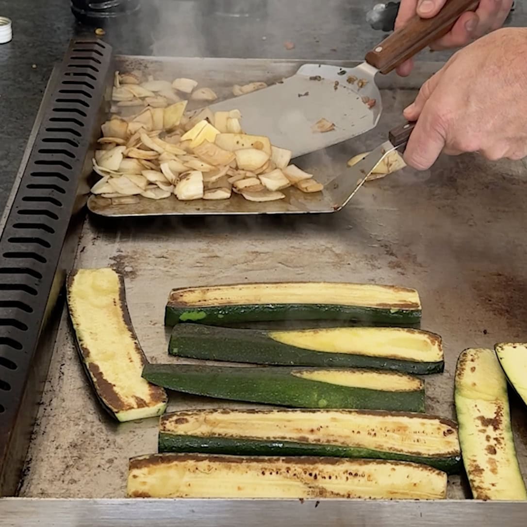 Grilling onions and zucchini on the griddle.