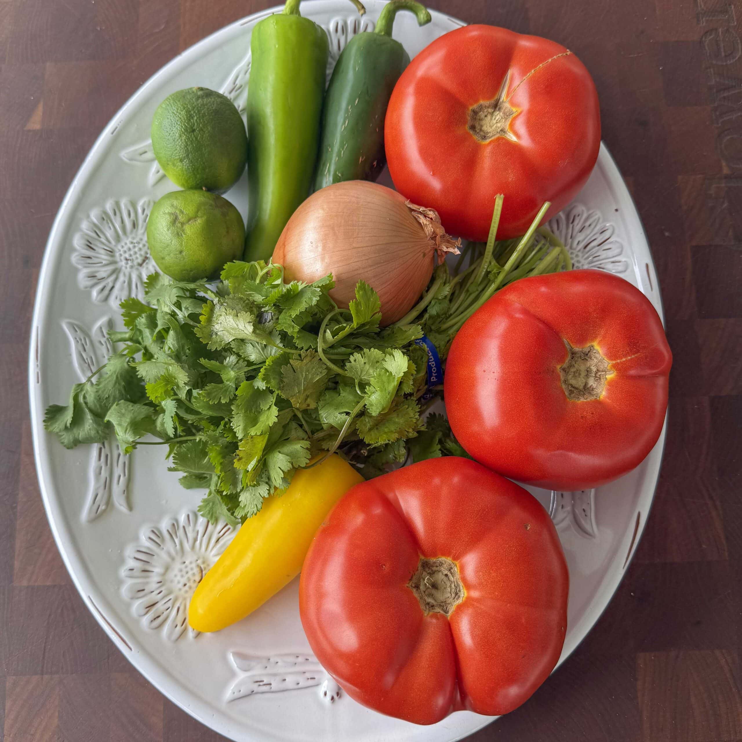 Tomatoes, cilantro and peppers on a plate.