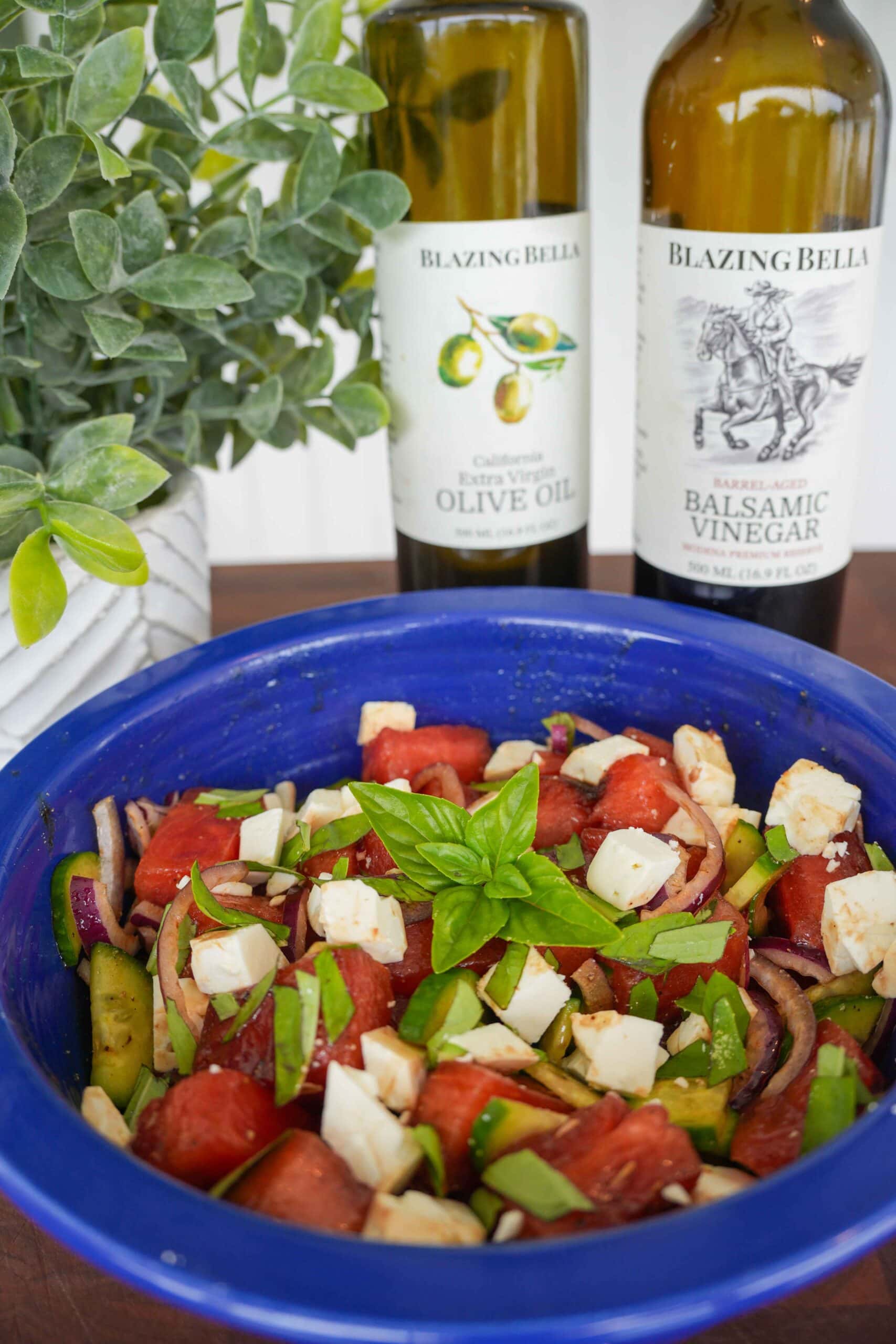 Watermelon Salad placed next to bottles of Blazing Bella Vinegar and olive oil.