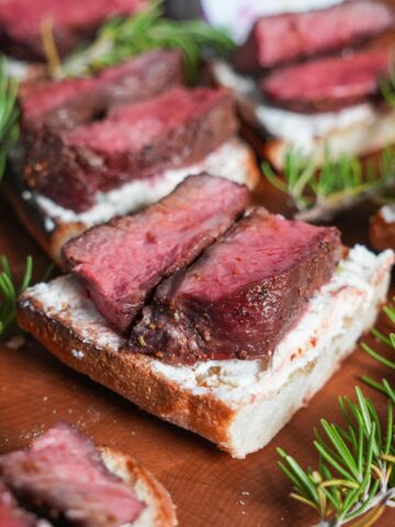 Steak on a crostini with rosemary.