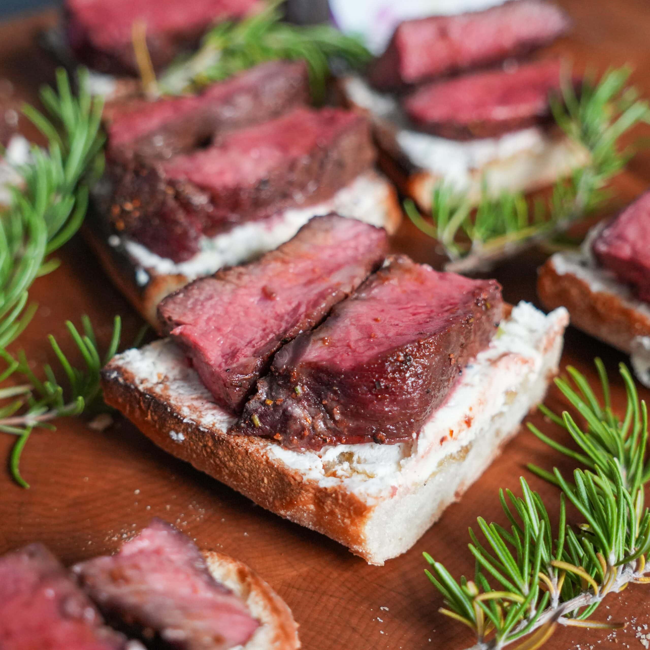 Steak on a crostini with rosemary.