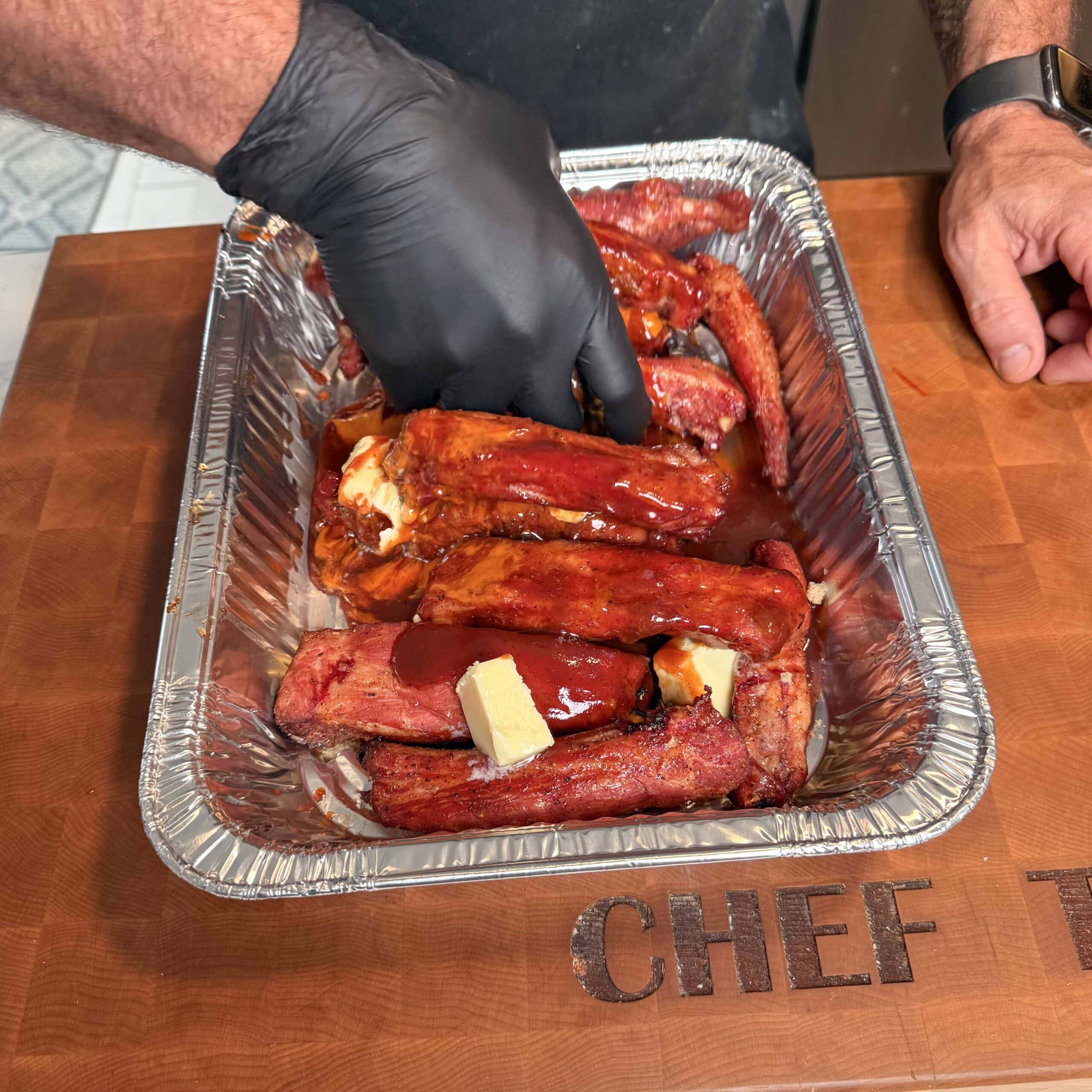 Ribs being tossed in sauce and butter.