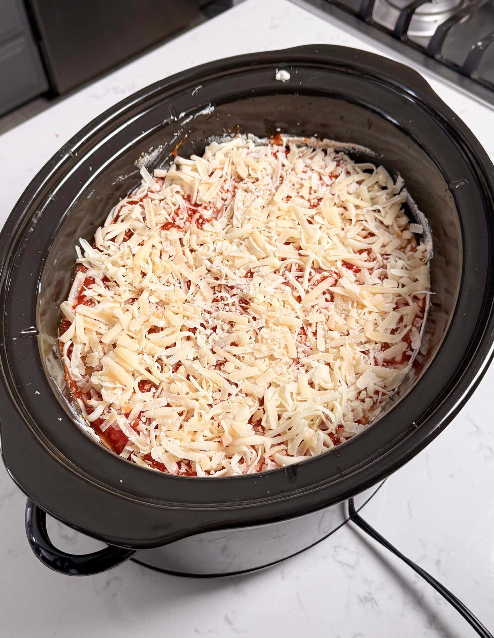 Cheese on top of lasagna in a crock pot.