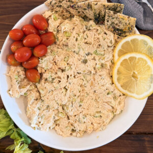 Chicken salad on a plate with tomatoes and crackers.