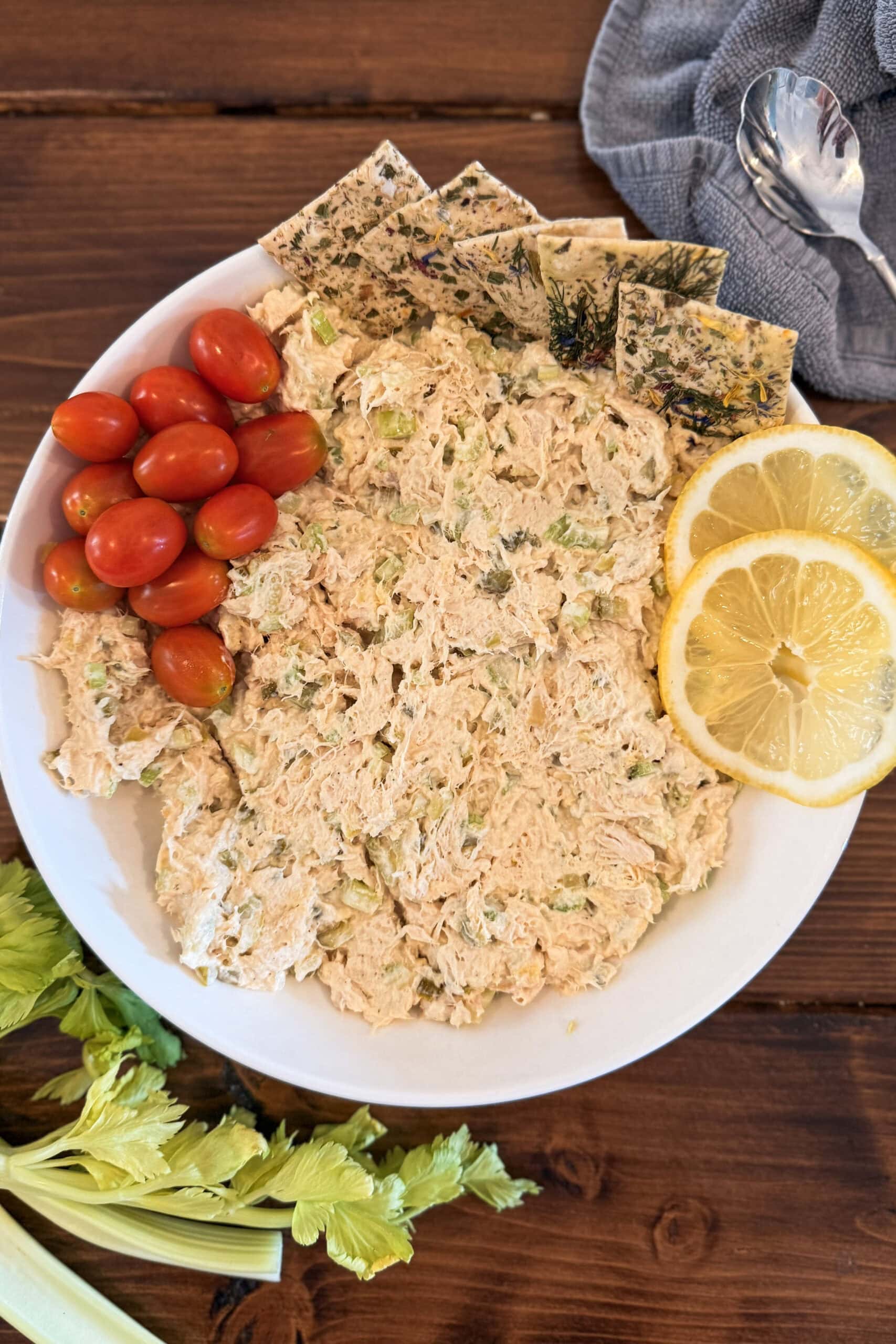 Chicken salad on a plate with tomatoes and crackers.