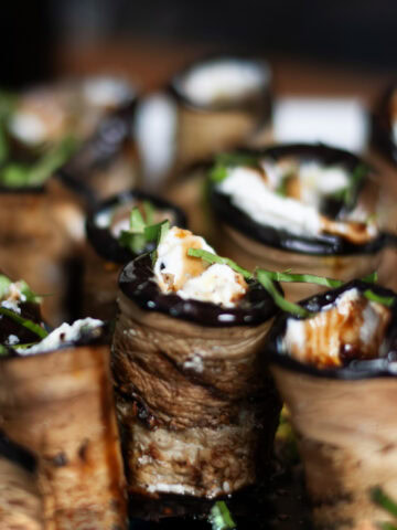 Grilled Eggplant roll ups on a plate with basil and balsamic.