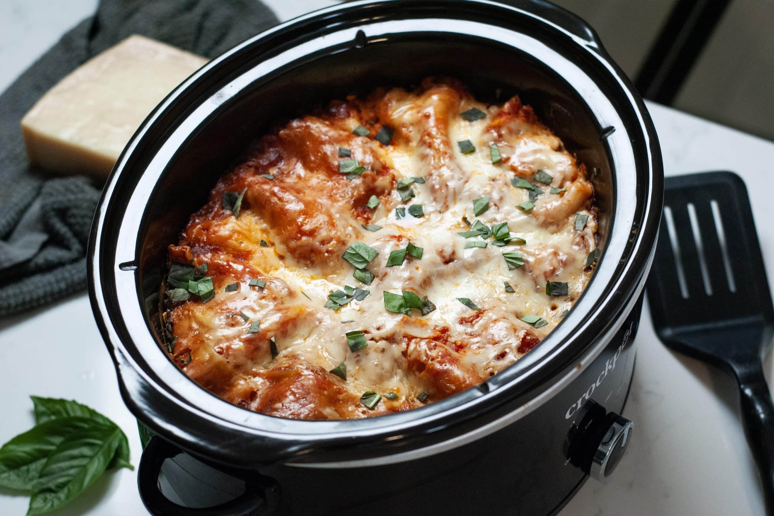 Lasagna in a crock pot by basil leaves.