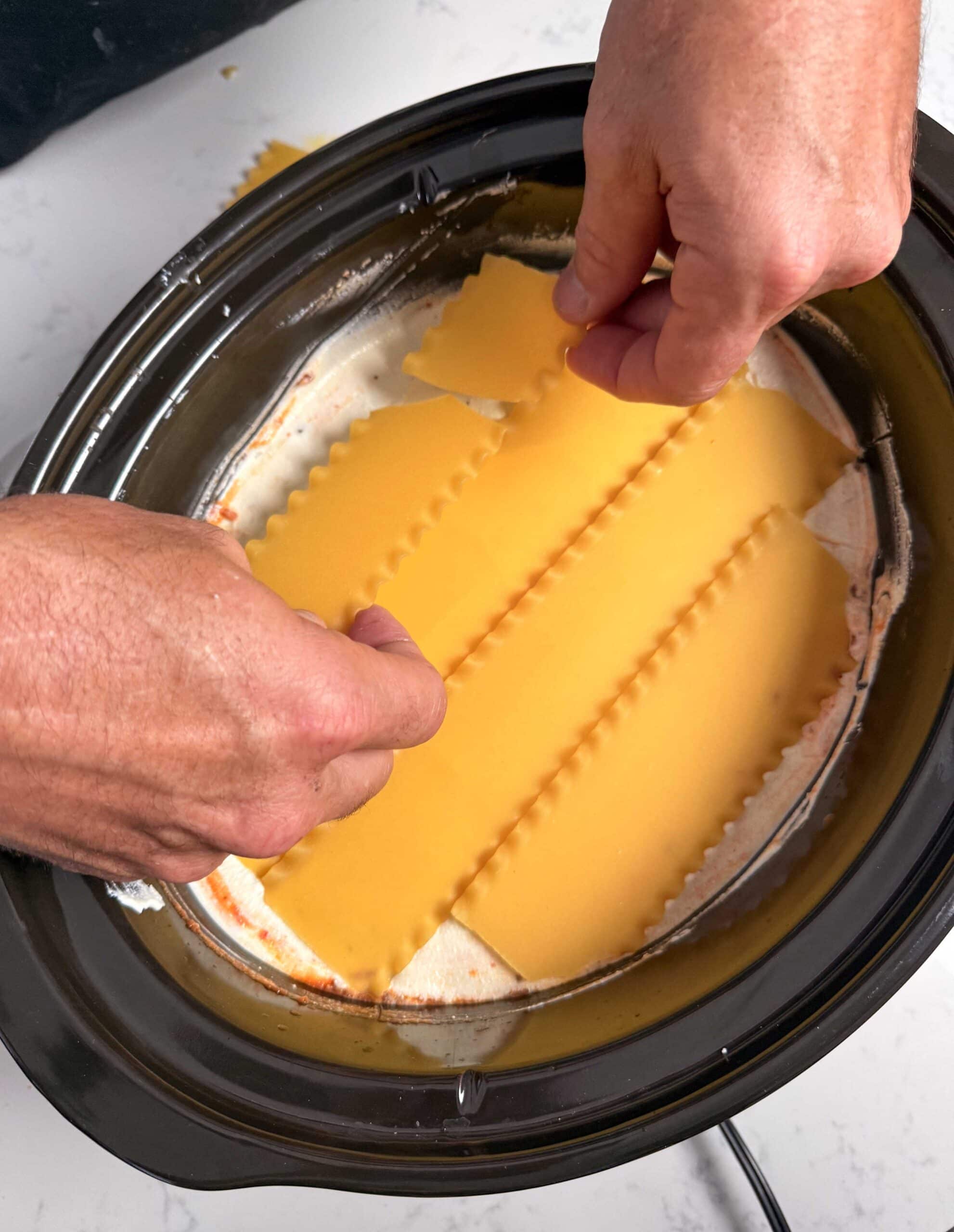 Lasagna noodles going into crock pot.