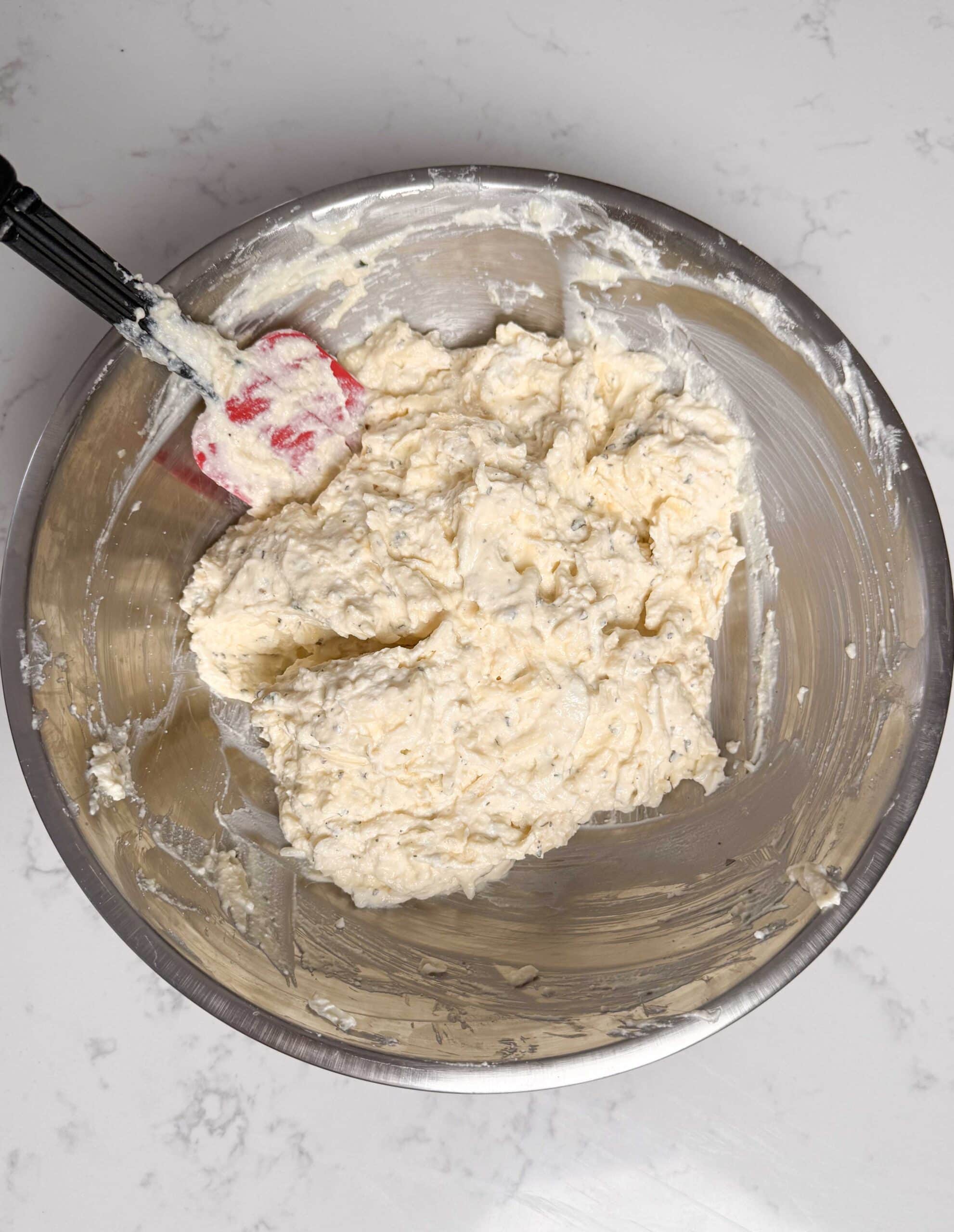 Ricotta cheese with seasonings in a bowl.