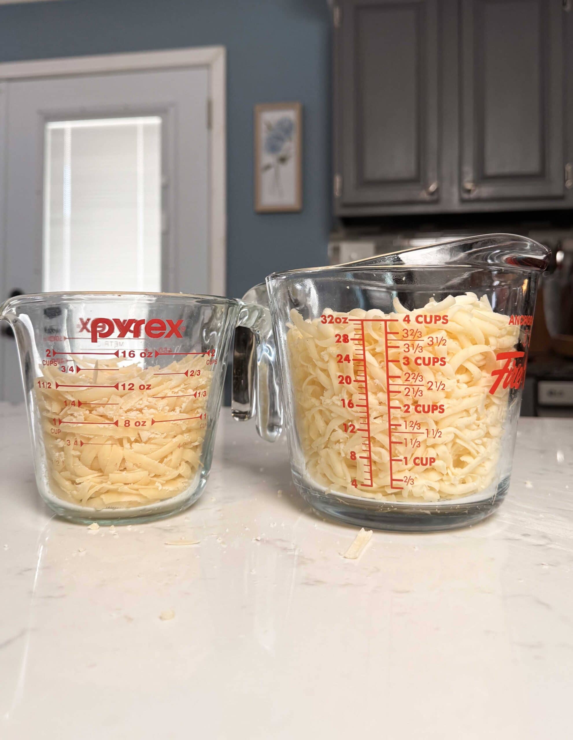 Two measuring cups full of shredded cheese.